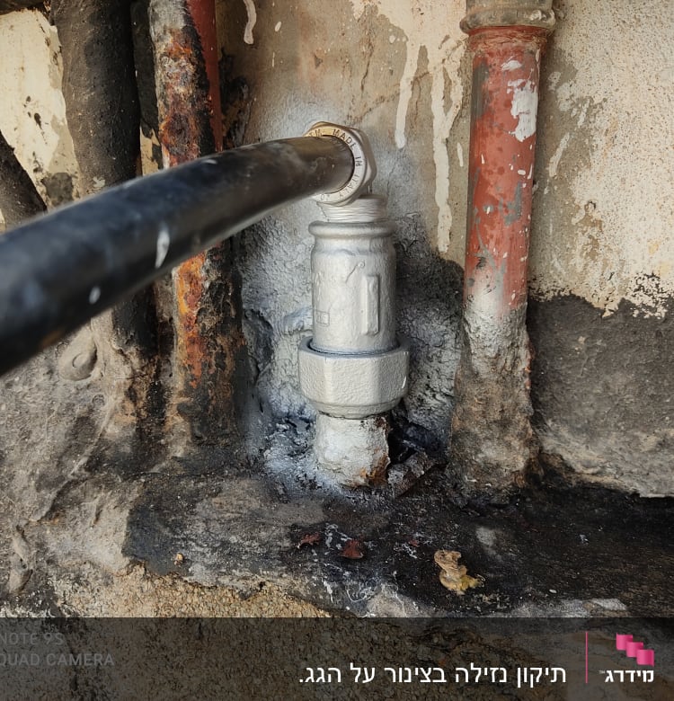 צינור שחור מחובר לשסתום מתכת על קיר